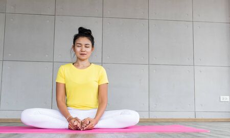 Beautiful asian young woman wearing sportswear practicing yoga in studio, natural light. Concept : yoga poses for beginner.の写真素材