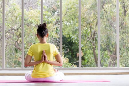 An Asian female yoga teacher wearing a yellow shirt is training her body to be strong and healthy with yoga.の写真素材