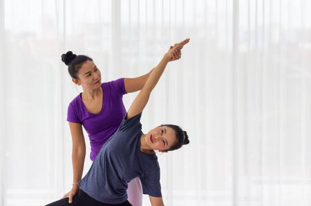 Asian yoga teachers teach students one-on-one in the gym to be healthy and strong.の写真素材