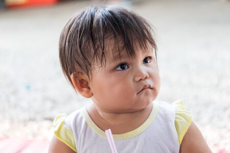 cute little asian girl sucking water from bottlesの写真素材