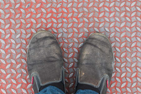 Selfie foot shoe color black on the lid, water pipes, sidewalks, top view.