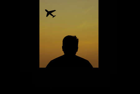 man alone looking at the plane through the window and silhouetteの写真素材