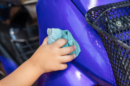 Girl's hand washing a motorbike to help the familyの写真素材