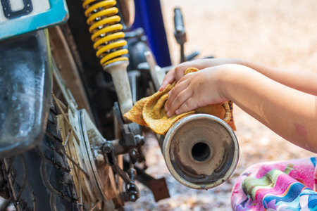 Girl's hand washing a motorcycle pipe to help the family