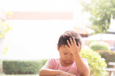 Young Asian girl in pink shirt feeling bored on chair. Depressed girl sits on chair with sad mood.の写真素材