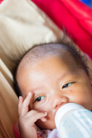 girl baby drinking milk from bottle. Baby holding bottle himself. sweet funny baby drinking.の写真素材