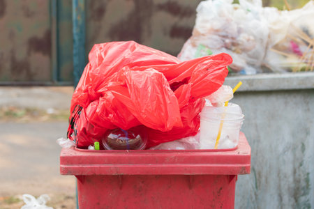 Garbage bins and containers full, overflowing, with bags falling on ground in residential area of Bordeaux, France, in a green container.の写真素材