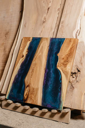 Exclusive handmade table of solid wood and epoxy resin on the background of wood boardsの写真素材