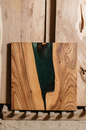 Exclusive handmade table of solid wood and epoxy resin on the background of wood boardsの写真素材