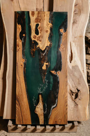 Exclusive handmade table of solid wood and epoxy resin on the background of wood boardsの写真素材