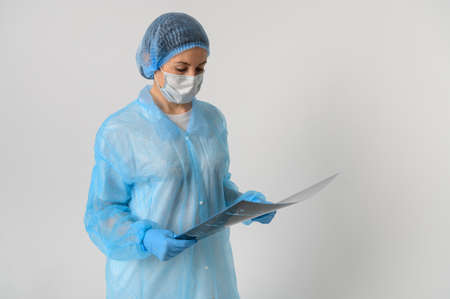 a nurse in a medical gown, mask and protective gloves