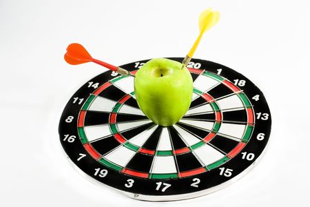 Darts in an apple (on a dartboard)の写真素材