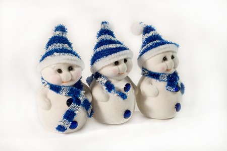 Row of three small snowmen wearing blue caps and scarves (as Christmas decorations)の写真素材