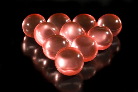 Rows of red aromatic bath balls (on a black background, with beautiful reflections)の写真素材