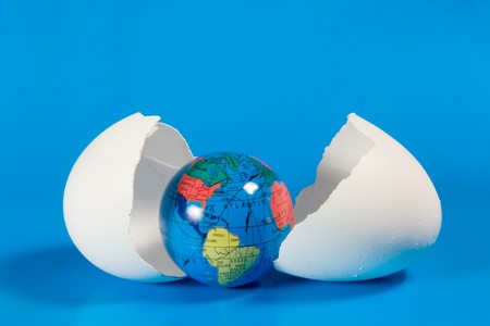 Small globe in broken eggshell (on a blue background)