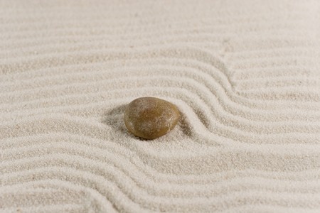 Closeup of a pebble on white sand (Zen style)