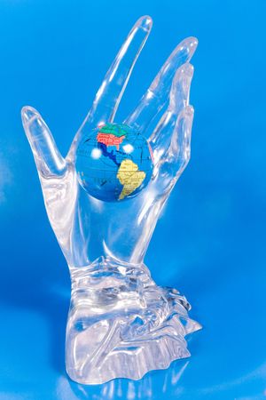 Small globe in a glass hand (on a bright blue background)の写真素材
