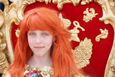 Smiling red-haired teenage girl wearing an antique princess dress (sitting on a princess throne)の写真素材