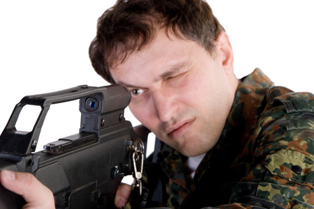 Portrait of a soldier aiming a gun with focus on the gun
