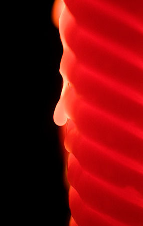 Blurred wax drop on a red candle in the dark as an abstract black and red backgroundの写真素材