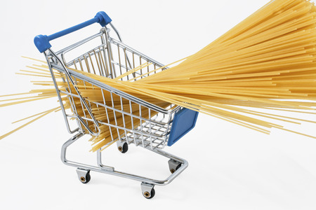 Shopping cart full of raw spaghetti (isolated on white)の写真素材