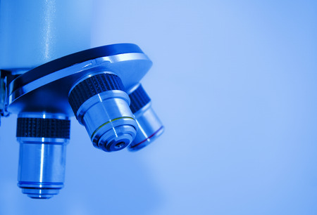 Closeup of microscope objectives (in blue tones, with empty space on the right for your text)