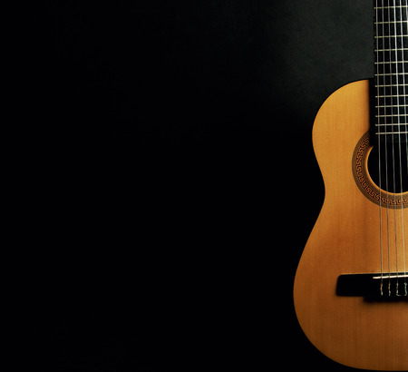 Half of a bright yellow acoustic guitar on a black background (with copy space)