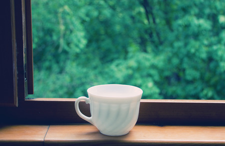 White coffee cup on a window sill (retro style)