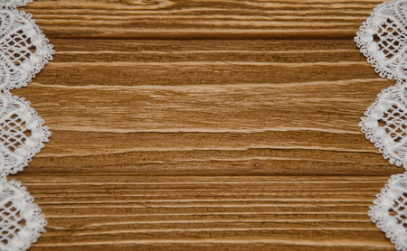 White lace on a worn brown wooden background forming a frame with copyspace in the center (selective focus) as a vintage backgroundの写真素材