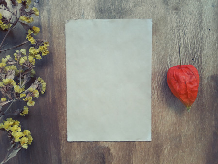 Dry autumn flowers and a blank old sheet of paper on a worn wooden background (view from the top or flat lay), retro styleの写真素材