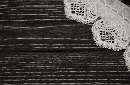 White lace on a black wooden background with copyspace on the left (selective focus) as a vintage backgroundの写真素材