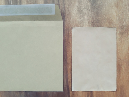 Blank old sheet of paper in an envelope on a worn wooden background (retro style)の写真素材