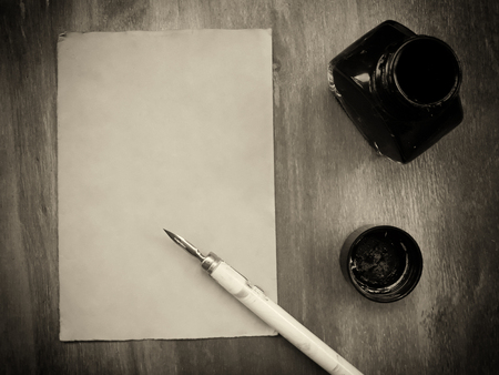 Blank old sheet of paper with a dip pen and an inkwell on a worn wooden background (view from the top or flat lay), retro style in sepiaの写真素材