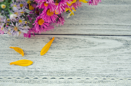 Bouquet of bright autumn flowers and three yellow petals on a gray wooden background and lace (with copy space on the right), selective focus, retro styleの写真素材