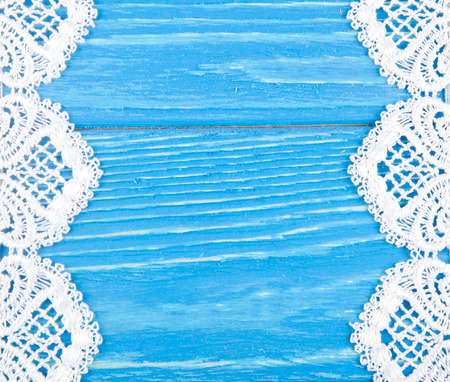 White lace on a worn bright blue wooden background forming a frame with copyspace in the center (as a vintage background)の写真素材