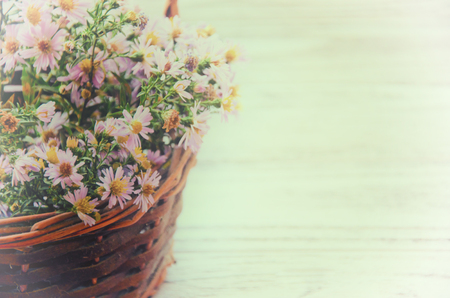 Pink and yellow autumn flowers in an old basket (faded film effect, vintage style), copy space on the rightの写真素材