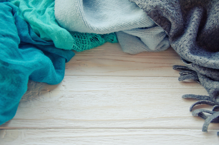 Pile of cozy scarves forming a frame on a white wooden background, selective focus (retro style)の写真素材