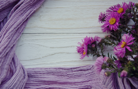 Bouquet of bright autumn flowers and a purple scarf forming a frame on a gray wooden background (with copy space in the center for your text), selective focusの写真素材
