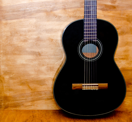 Body of a black acoustic guitar against a grungy wooden background, copy space on the left for your textの写真素材