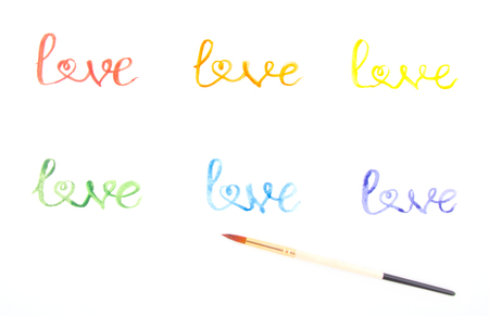 Word Love written with watercolor paint of different rainbow colors and a brush (with one of the letters shaped as a heart), isolated on whiteの写真素材