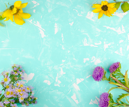 Bright violet and yellow flowers forming a frame on a turquoise cracked concrete background (with copy space in the center for your text), top viewの写真素材