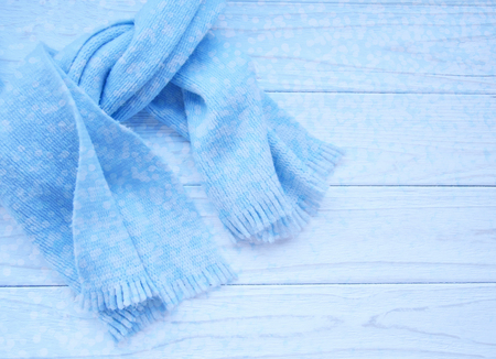 Light blue scarf tied up on a wooden background (copy space on the right, beautiful blurred blue festive bokeh in the front) as a New Year, Christmas or winter backgroundの写真素材