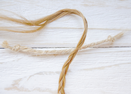 Woman braid (natural blonde hair) in contrast to man-made fiber on a worn wooden backgroundの写真素材