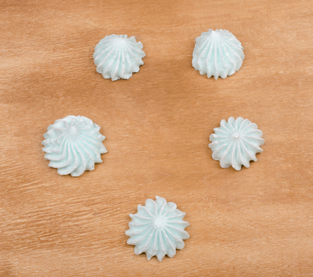 Freshly baked meringue cookies of mint color forming a circle on a brown wooden background (top view)の写真素材