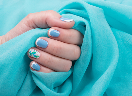 Beautiful female hand with manicured nails holding a folded scarf of mint colorの写真素材
