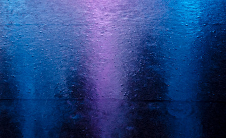 Blurred neon city lights reflected in a puddle and raindrops during the rain (as an abstract colorful blurred background), soft focusの写真素材