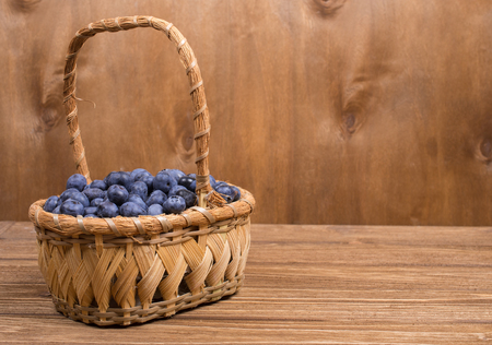 Basket with blueberries against a wooden background (copy space on the right)の写真素材
