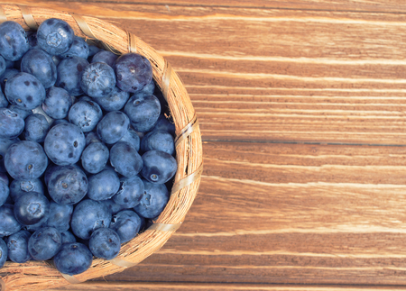 Top view of a basket with blueberries against a wooden background, retro style (copy space on the right)の写真素材