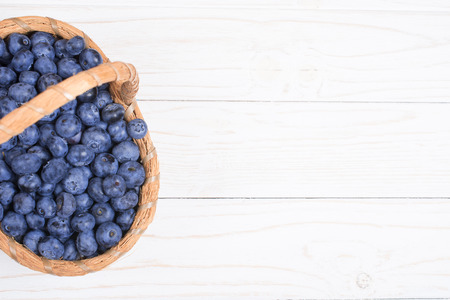 Top view of a basket with blueberries on a white wooden background (copy space for your text)の写真素材
