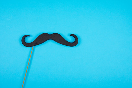 Moustache on a stick against a blue background (copy space on the right), minimal conceptの写真素材